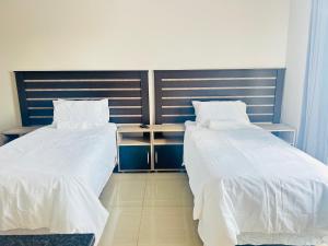 two beds with white sheets in a room at Rainow guest house in Burgersfort