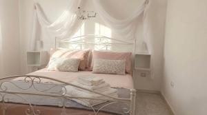 a white bedroom with a bed with pink pillows at villa mina con vasca idromassaggio in Taranto