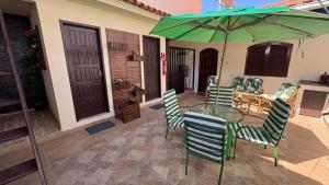 a table and chairs with a green umbrella on a patio at Hostel Arraial in Arraial do Cabo