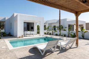 a villa with a swimming pool and two chairs at Villa Salty Sun 2 in Kremasti