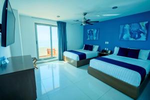 a blue bedroom with two beds and a television at Hotel Tramonto Mazatlan in Mazatlán +40 photos