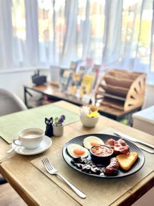 a plate of breakfast food on a table with a cup of coffee at United Home B&B in Manchester