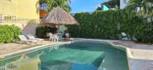 a swimming pool with two chairs and a straw umbrella at Departamento Arena- Oasis del Mar in Progreso