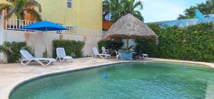 a swimming pool with chairs and an umbrella at Departamento Arena- Oasis del Mar in Progreso
