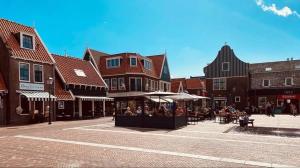 a street in a town with tables and umbrellas at Harbour Stay Volendam in Volendam