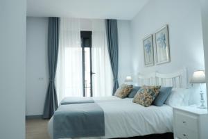 a bedroom with a white bed with blue walls at Balcones a San Pedro in Osuna