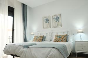 a white bed with two pillows in a bedroom at Balcones a San Pedro in Osuna