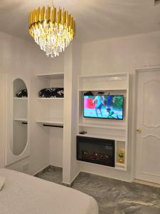 a living room with a television and a chandelier at Hospedaje El Buen Descanso in Salento
