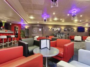 a waiting room with red chairs and a table at ibis Styles Paris Roissy-CDG in Roissy-en-France