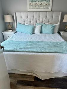 a large bed with blue and white sheets and pillows at North Cape- Behing Trading Post - Pet Friendly in Cape San Blas