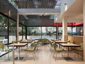 a restaurant with tables and chairs and large windows at Novotel Athens in Athens