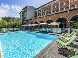 a large swimming pool with chairs and a building at Novotel Toulouse Centre Compans Caffarelli in Toulouse