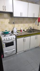 a kitchen with a stove and a sink and white cabinets at Monoambientes Peatonal - con cochera in Corrientes