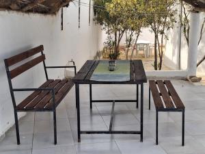 a wooden table with two benches and a table and chairs at Maison Amina Villa Novel in Triffa