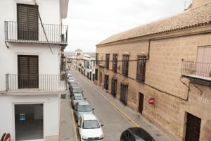 a row of cars parked on a street between buildings at Balcones a San Pedro in Osuna