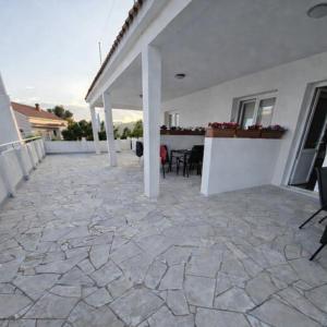 a patio of a white house with a table and chairs at Apartmani Tomic in Zavalatica +81 photos