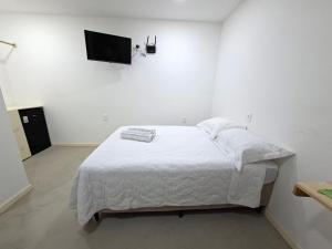 a white bedroom with a bed and a flat screen tv at Recanto de Boipeba in Ilha de Boipeba +2 photos