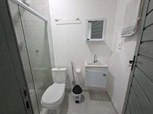 a white bathroom with a toilet and a sink at Recanto de Boipeba in Ilha de Boipeba