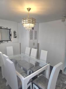 a dining room table with white chairs and a chandelier at Hospedaje El Buen Descanso in Salento