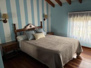 a bedroom with a bed with blue and white stripes at Posada El Jardin in Santillana del Mar