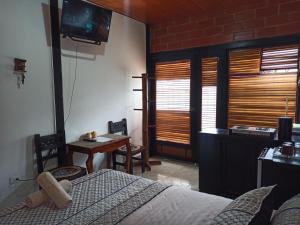 a bedroom with a bed and a desk and a television at Home Capybara Stay in Mindo