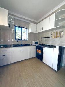 a large kitchen with white cabinets and a window at Oasis Residence in Arusha