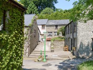an alley with stone buildings and a green street light at Juniper - 28060 in Wheddon Cross