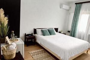 a bedroom with a large white bed with green pillows at Vila Macris in Eforie Nord