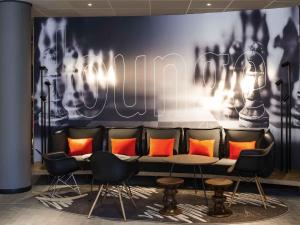 a bar with chairs and a table with orange pillows at ibis Gent Centrum St. Baafs Kathedraal in Ghent