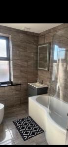 a bathroom with a tub and a sink and a toilet at Coastal Nest in Hollington +16 photos