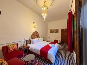 a bedroom with a large bed and a red chair at Riad Fez Guests in Fez
