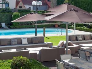 a patio with chairs and umbrellas next to a pool at Novotel Brugge Centrum in Bruges