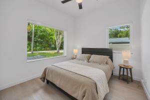 a white bedroom with a bed and two windows at Ember & Oak - Modern Retreat Near Downtown - Pets in St. Augustine