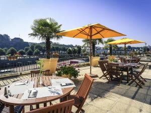 Eine Gruppe von Tischen und Stühlen mit Sonnenschirmen auf einer Terrasse in der Unterkunft Mercure Saint Lô Centre in Saint Lo