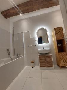 a bathroom with a sink and a tub and a mirror at Moulin de Monpoisson in Le Puy