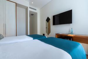 a bedroom with a bed with a television on the wall at Golden City Boutique Hotel Tirana in Tirana
