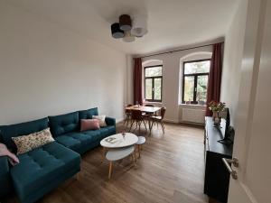 a living room with a blue couch and a table at Gäste-Appartements Morgensonne & Sonnenschein in Dresden