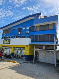 a blue and yellow building with a car parked in front at Hostal Haziel in Salinas