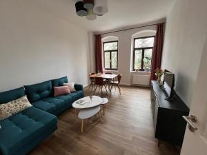 a living room with a blue couch and a table at Gäste-Appartements Morgensonne & Sonnenschein in Dresden
