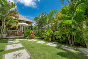 a garden with a house with a lawn at Incense Impossible Beach Boutique Hotel - Adults Only in Uluwatu
