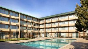 a large building with a swimming pool in front of it at Plaza Hotel Denver Central in Denver