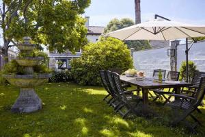 a table with an umbrella and a fountain in a yard at Casa La Palomba in Cudillero