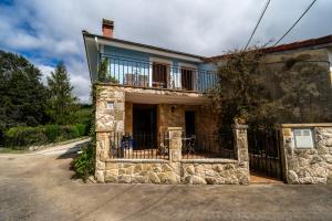a stone house with a balcony on top of it at El Caracol azul del Plano in Siero