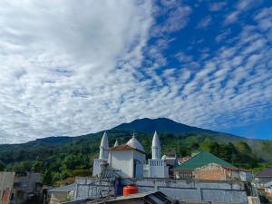 a building with white domes and a mountain in the background at Mutiara Guest House Syariah in Padangluar