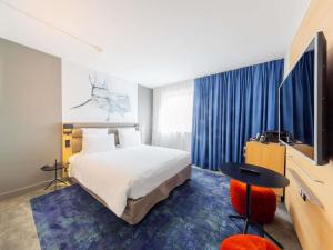 a hotel room with a bed and a flat screen tv at Mercure Paris Massy Gare TGV in Massy