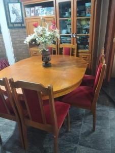 a wooden table with chairs and a vase of flowers on it at Elba Cabañas in Villa Carlos Paz +10 photos
