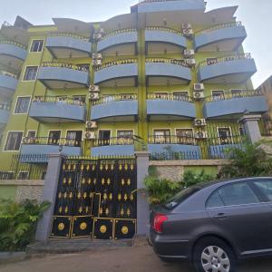 a blue and yellow building with a car parked in front at Sweetland Vesidences in Yaoundé