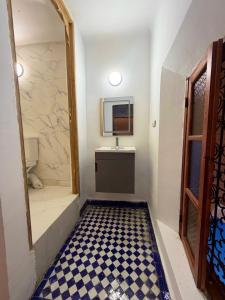 a bathroom with a sink and a mirror and a checkered floor at Riad Fez Guests in Fez