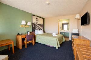 a hotel room with a bed and a desk at Super 8 by Wyndham Barstow in Barstow