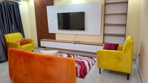 a living room with two chairs and a tv at Cherished Homes in Ikeja